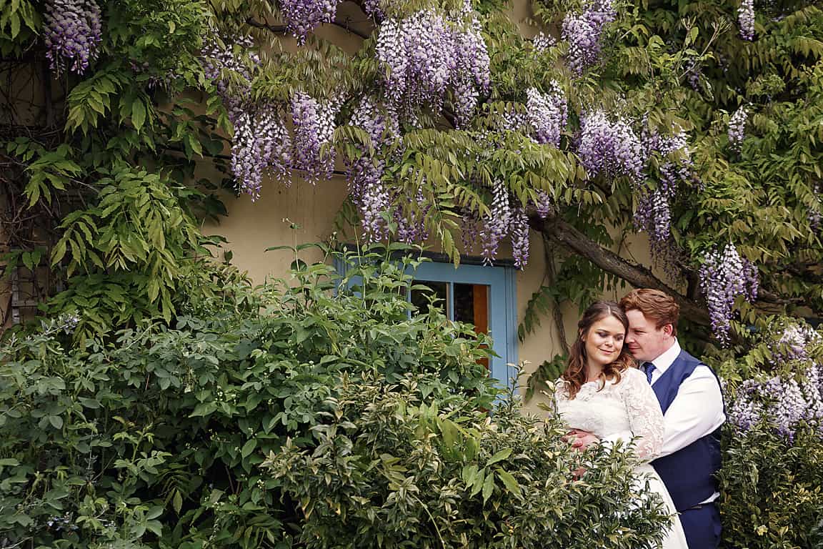 Bride and Groom in Spring Garden full of wisteria at Cambridgeshire Garden Wedding Venue