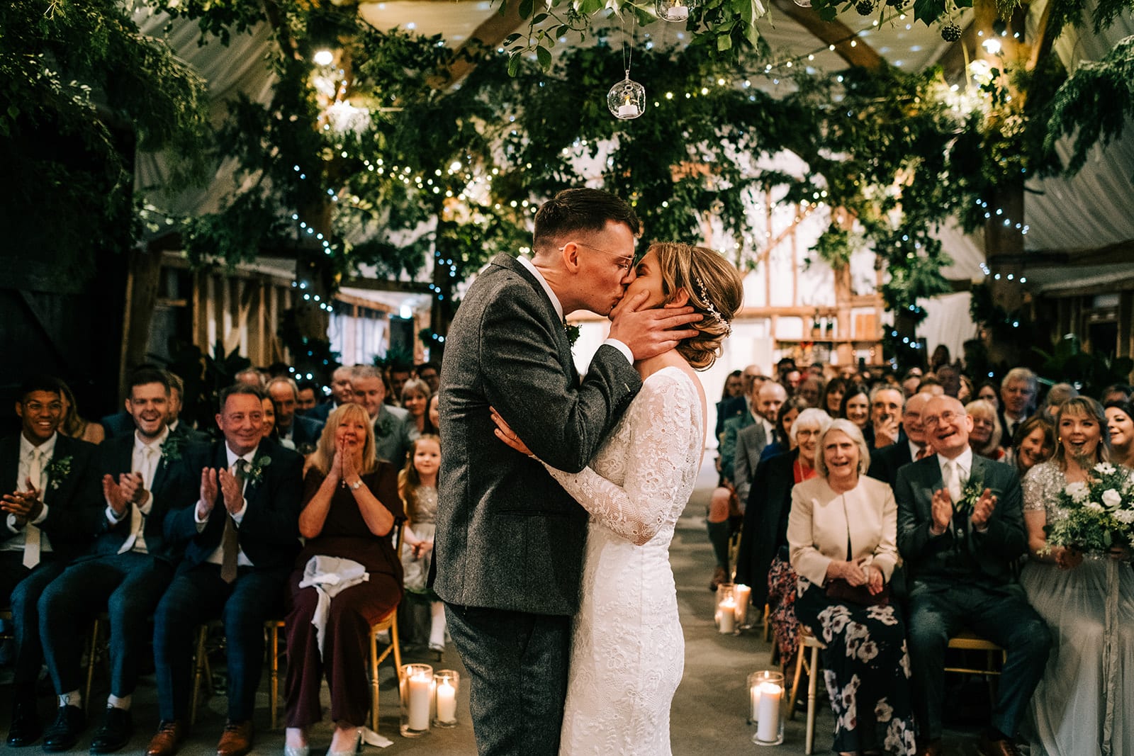 Bride-and-groom-kiss-at-South-Farm-Barn-wedding-ceremony-as-guests-clap-and-look-on-Lee-Allison-Photography