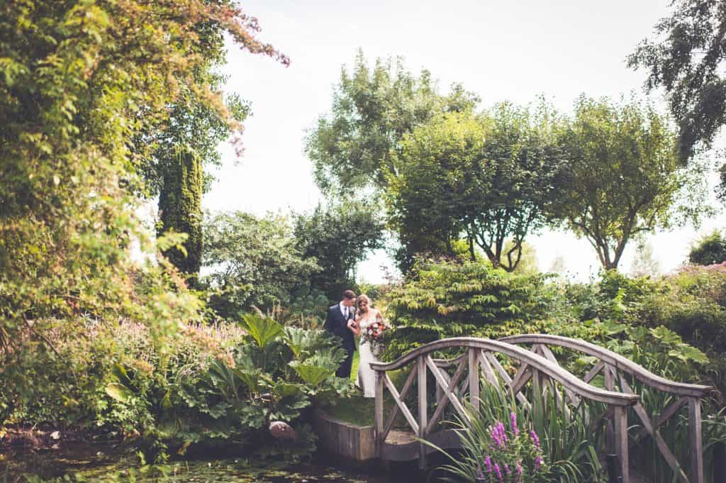 Bride and Groom in beautiful garden wedding venue bridge over pone