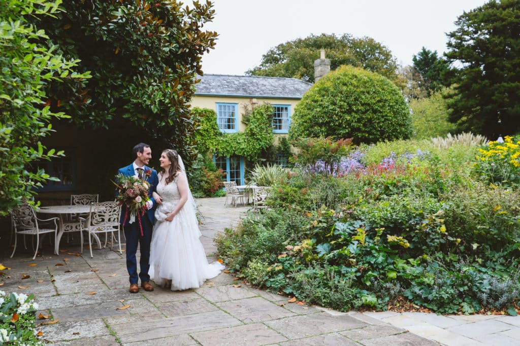 Groom holds the brides bouquet as they take a moment in South Farms Stunning Gardens