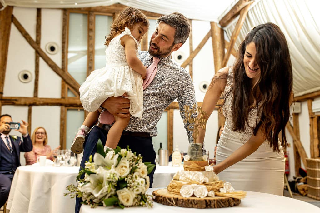 Bride and groom cut cake at rustic barn wedding venue 