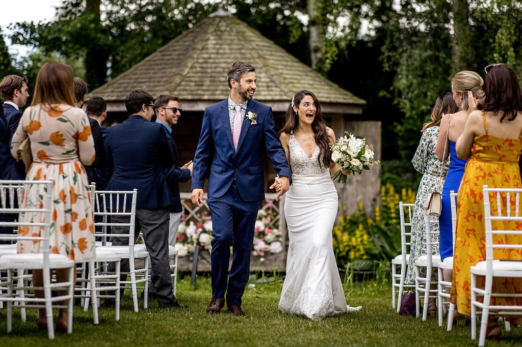 Bride and groom walk down the aisle after just being married in garden wedding ceremony