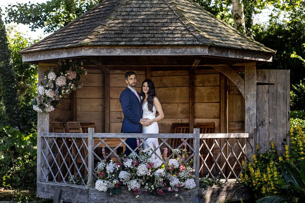 Bride and Groom in rustic garden summerhouse decorated with flowers